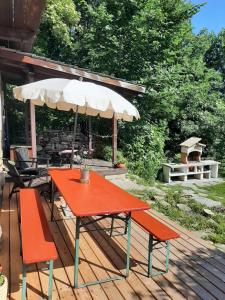 a red table and two benches on a deck with an umbrella at Casa Alex in Roure Turin