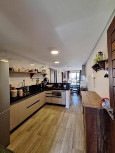 a large kitchen with wooden floors and a counter in it at Apto Solluar Flecheiras Trairi in Trairi