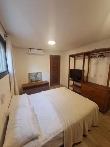a bedroom with a large white bed and a television at Apto Solluar Flecheiras Trairi in Trairi