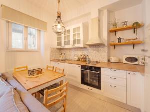 a kitchen with white cabinets and a wooden table at Nena's Volto, Campiello living in Corfu