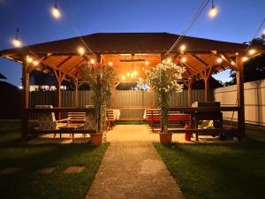 a gazebo with a table and benches and lights at Casa Alba - Tasnad in Tăşnad