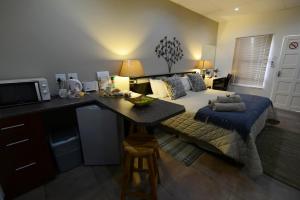 a bedroom with a bed and a desk with a microwave at Carters Rest Guesthouse in Kimberley