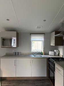 a kitchen with white cabinets and a sink at Sea Breeze Lodge in Longniddry