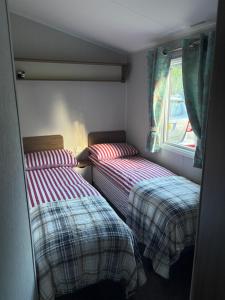 two twin beds in a small room with a window at Sea Breeze Lodge in Longniddry