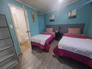 two beds in a room with blue walls at HOSTAL EL ARoMO CHILLÁN in Chillán
