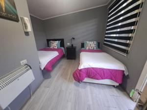 a bedroom with two beds with pink and white sheets at HOSTAL EL ARoMO CHILLÁN in Chillán