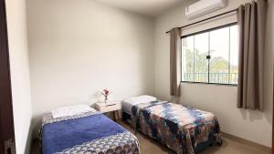 two beds in a room with a window at Apartamento com 2 quartos próximo do centro in Sinop