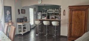 a kitchen with a bar with three stools at La maison dans les vignes in Châteauneuf-sur-Charente