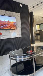 a glass table in a room with a tv on a wall at Ali in Mawāliḩ
