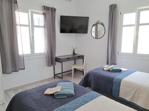 a bedroom with two beds and a desk and windows at ALSIDE Apartment in Aegiali