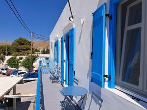 a balcony with blue doors and tables on a building at ALSIDE Apartment in Aegiali