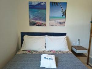 a bedroom with a bed with two pictures on the wall at Sol, Mar e Tranquilidade a poucos passos do Caminho de Moisés com Varanda Privativa e Estacionamento in Maragogi