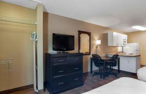 a hotel room with a desk with a television and a bedroom at Extended Stay America Suites - San Diego - Oceanside in Oceanside