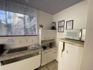 a small kitchen with a microwave and a refrigerator at kitnet Residencial Ozzy com Garagem Coberta em Betim in Betim