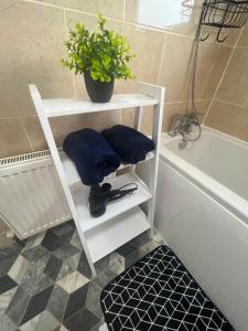 a white shelf next to a bath tub with a plant at Large river side house, parking,for 9 people in Bedford +15 photos