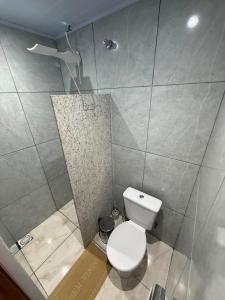 a bathroom with a white toilet in a room at kitnet Residencial Ozzy com Garagem Coberta em Betim in Betim +7 photos