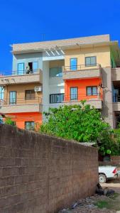 an apartment building with a brick wall in front of it at Hôtel Résidence Aïcha Tambacounda in Tambacounda