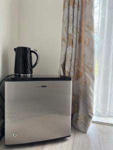 a kettle on top of a refrigerator next to a window at King room with garden access in Raynes Park