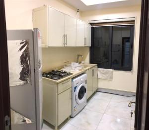 a kitchen with a stove and a washing machine at موتيل روزا عينكاوا in ‘Aynkāwah