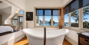 a bath tub in a room with a bed and windows at Casa Con Vista Luxury Waterfront Home, Sleeps 10 in Hobart
