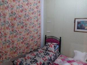 a small bedroom with a bed with a flowery curtain at إقامة تسنيم in Selouane