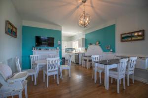 a dining room with white tables and white chairs at Silver Lining Inn and Motel in Chéticamp