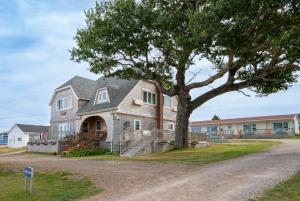 a large house with a tree in front of it at Silver Lining Inn and Motel in Chéticamp
