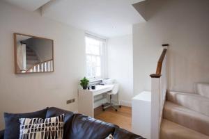 ein Wohnzimmer mit einer Couch, einem Schreibtisch und einem Spiegel in der Unterkunft Finchley Central Spacious 3 bed triplex loft style apartment in Hendon