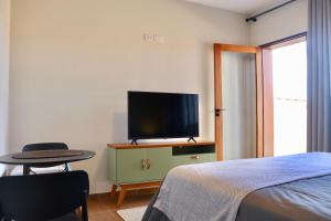 a bedroom with a tv and a table and a bed at Fiorelli 401 in Cunha