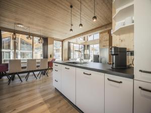 a kitchen with white cabinets and a dining room at Bichlbach Chalet with sauna in Bichlbach +21 photos