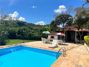 a pool with chairs and umbrellas next to a house at Recanto Rosa Maria in Monte Sião