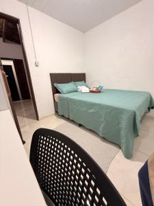 a bedroom with a bed with a green blanket and a chair at BARRA NOVA CASCAVEL CEARÁ-Casa Solaris in Cascavel
