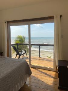 a bedroom with a large sliding glass door to a beach at Ocean breeze Villas in La Ceiba