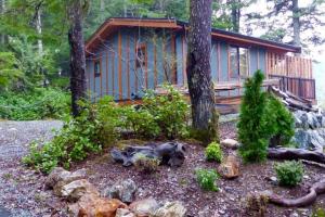 a dog laying in the yard in front of a cabin at The Great Escape - Port Renfrew in Port Renfrew