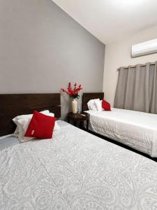 two beds with red pillows in a room at Hotel Puerta de Jade in Ciudad Valles