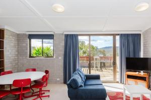 a living room with a table and chairs and a tv at Tanderra 17 28 Park Road in Jindabyne