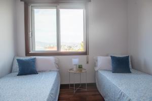 two beds in a room with two windows at Laxes do Mar in Baiona