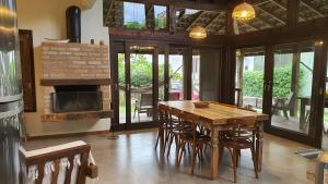 a dining room with a wooden table and a fireplace at Surf a poucos passos do mar, casa com lareira in Garopaba