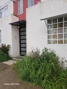 a white house with a black door and some plants at La comodidad a tu alcance in Bata