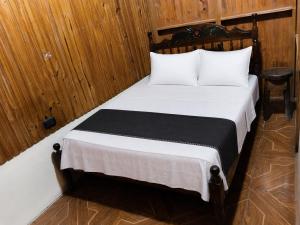a bedroom with a bed with white sheets and wooden walls at Maye WOOD APT in Uvita
