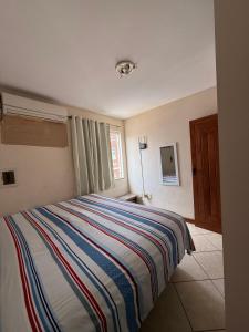 a bedroom with a bed with a striped blanket at Temporada Ilhéus Centro in Ilhéus