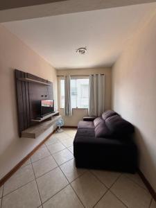 a living room with a couch and a flat screen tv at Temporada Ilhéus Centro in Ilhéus