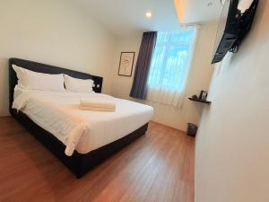 a bedroom with a bed with white sheets and a window at Soho Tabuan Kuching in Kuching
