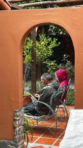 two people sitting in chairs on a patio with their cell phones at Casalma hospedaje y bienestar in Salta