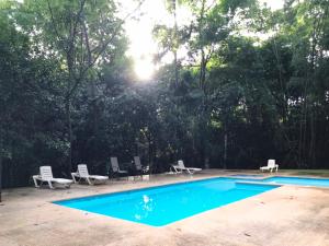 a swimming pool with chairs and the sun shining at Fuga Ecolodge casa de campo in Carara