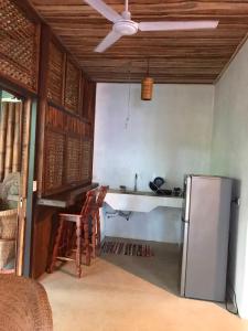 a kitchen with a refrigerator and chairs in a room at Fuga Ecolodge casa de campo in Carara
