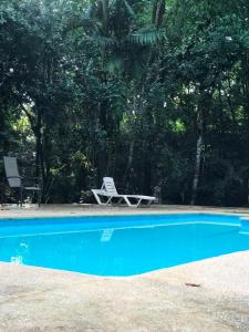 a blue swimming pool with a chair and a table at Fuga Ecolodge Casa grande in Carara +5 photos
