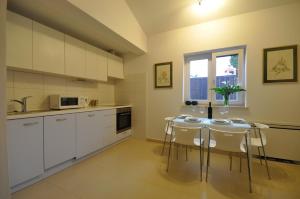 a kitchen with white cabinets and a table with chairs at Apartmani Val in Pula +37 photos