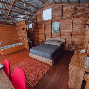 a bedroom in a log cabin with a bed and chairs at La Alborada Glamping in Filandia