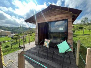 a tiny house with two chairs on a deck at La Alborada Glamping in Filandia